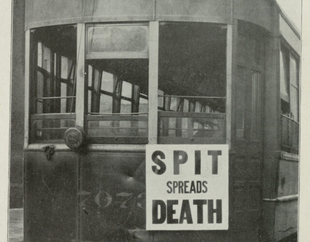 Black and white photograph of a trolley with a sign on front that says "spit spreads death".