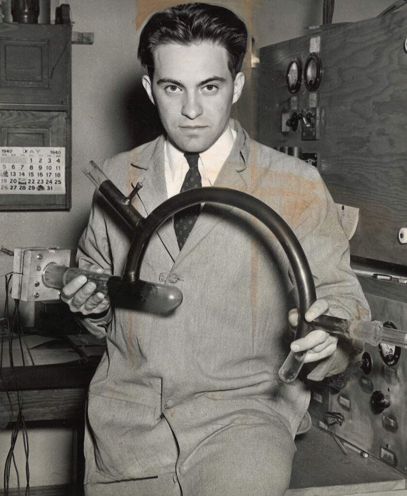 black and white photo of a man holding a rounded glass tube