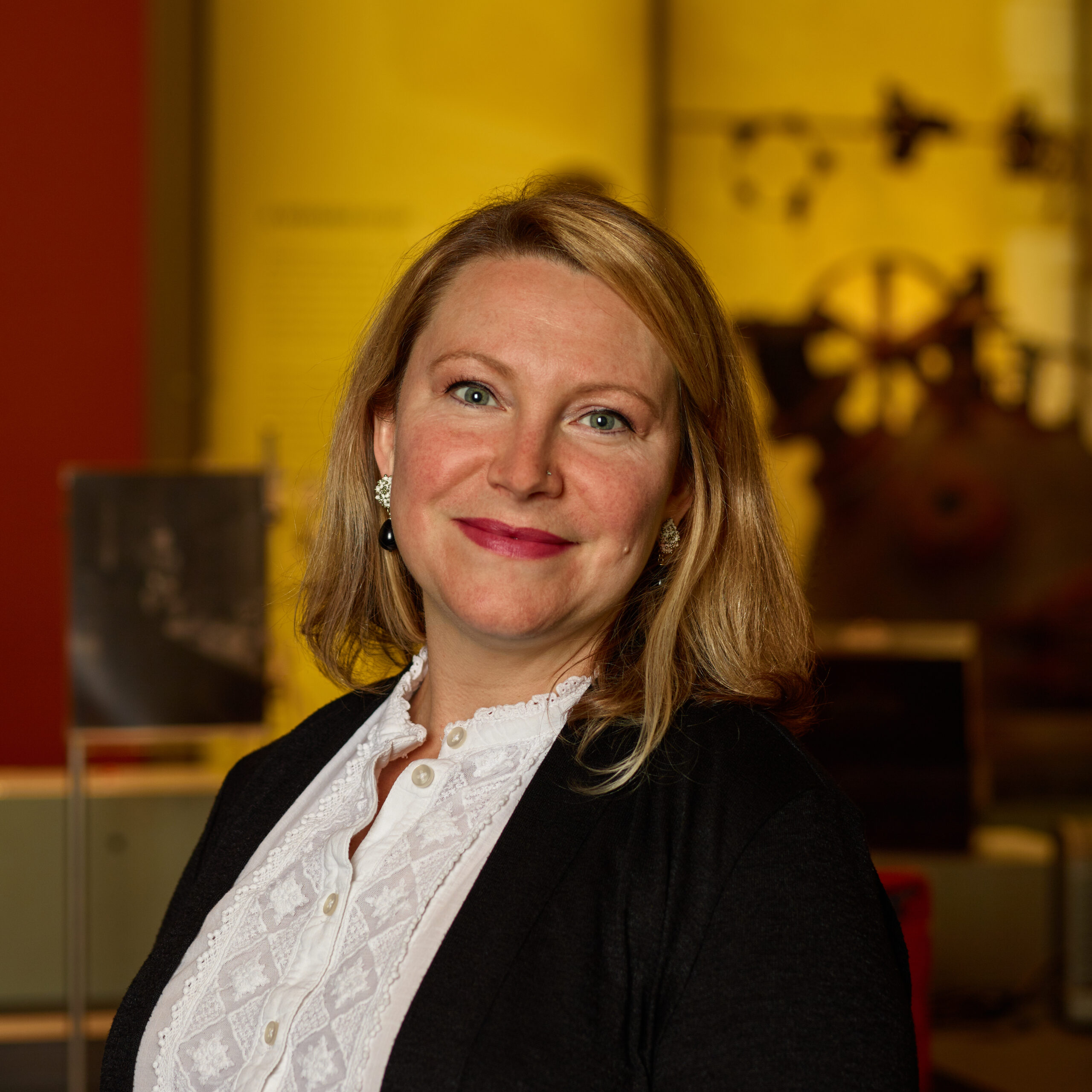 Ashley in museum wearing white lace blouse under black blazer