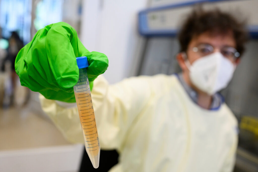 Man in surgical mask holding up a lab sample