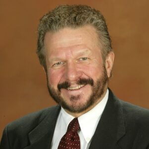 Donald wears a suit and maroon tie. There is an orange background.