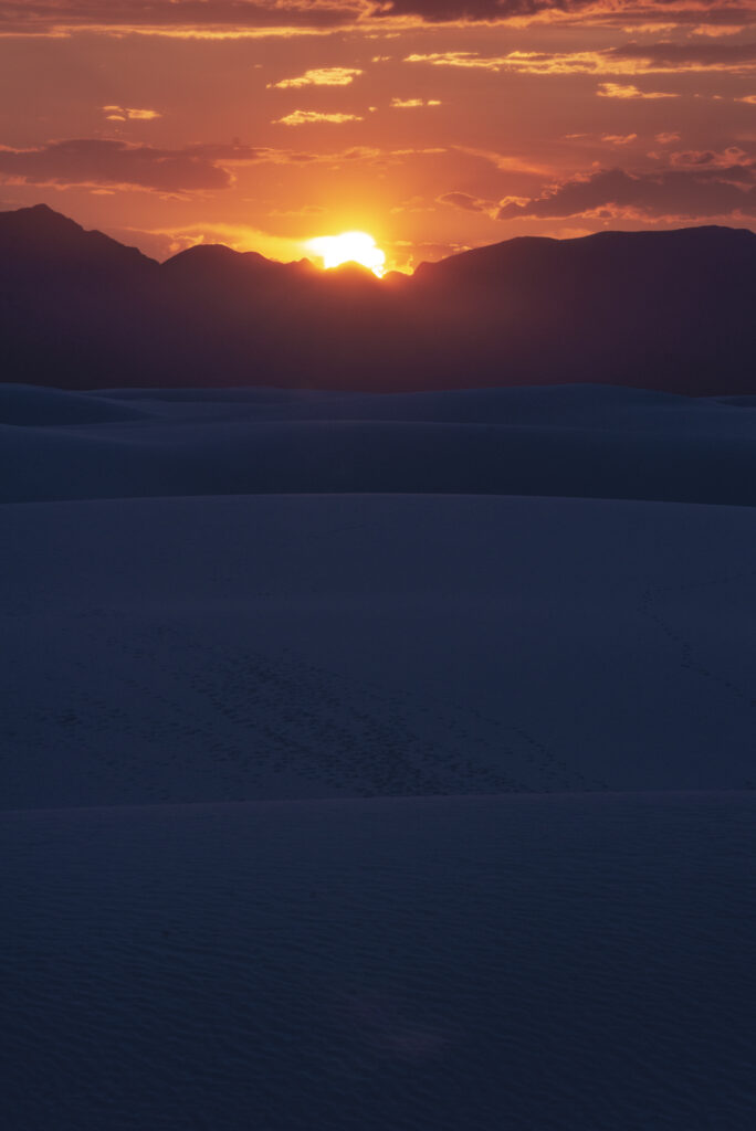 Photo of the sun peaking above the silhouette of a mountain range