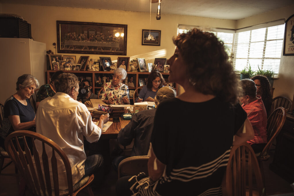 A group of women working around a dining room table below a reproduction of Leonardo's Last Supper