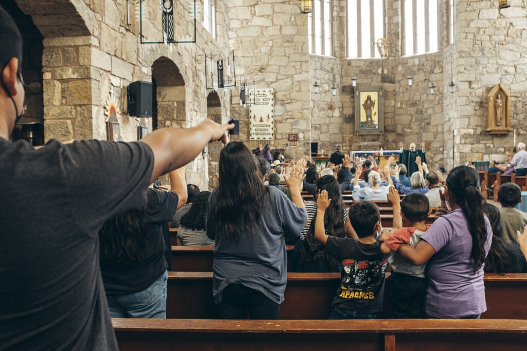 Photo from behind of parishioners worshipping in stone church