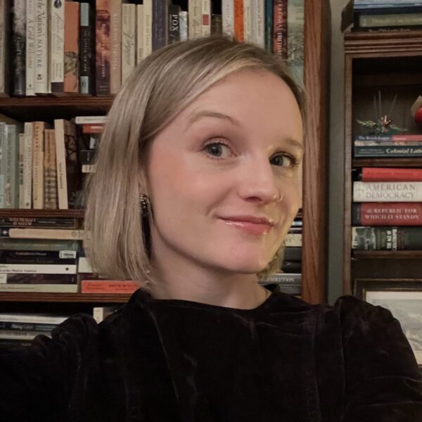 Eleanor Webb wearing black, sitting in front of bookcase