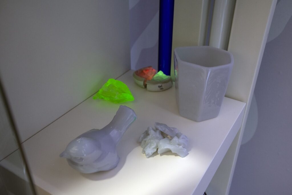 A glass bird and vase plus other glass pieces glowing under black light