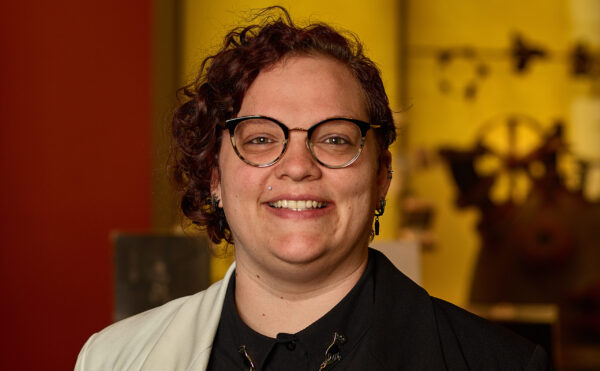 Erin in museum wearing glasses, black shirt, white blazer