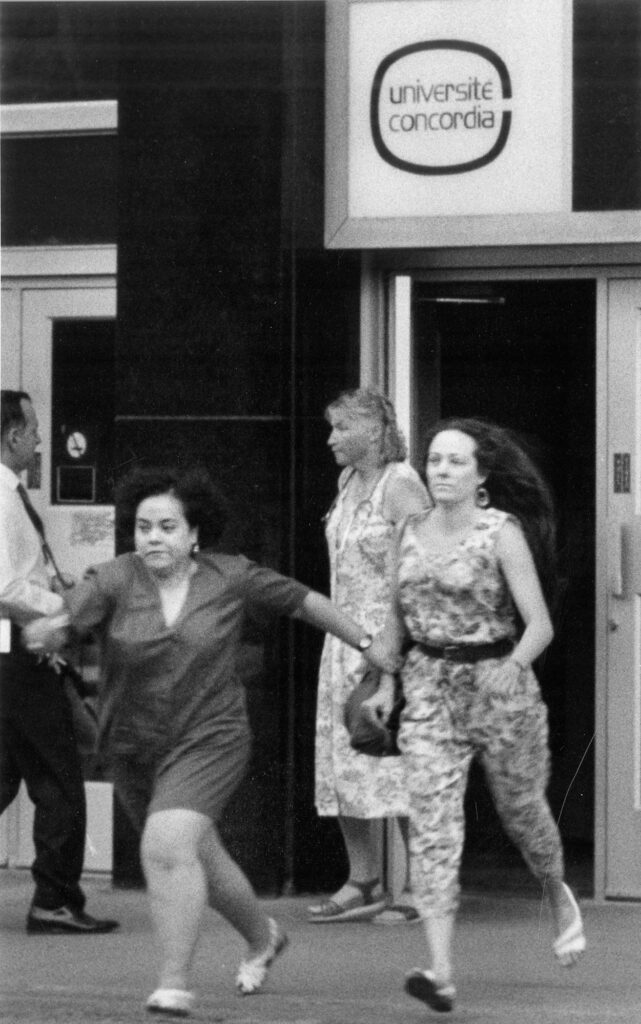 Black and white photo of two women running away from a building entrance