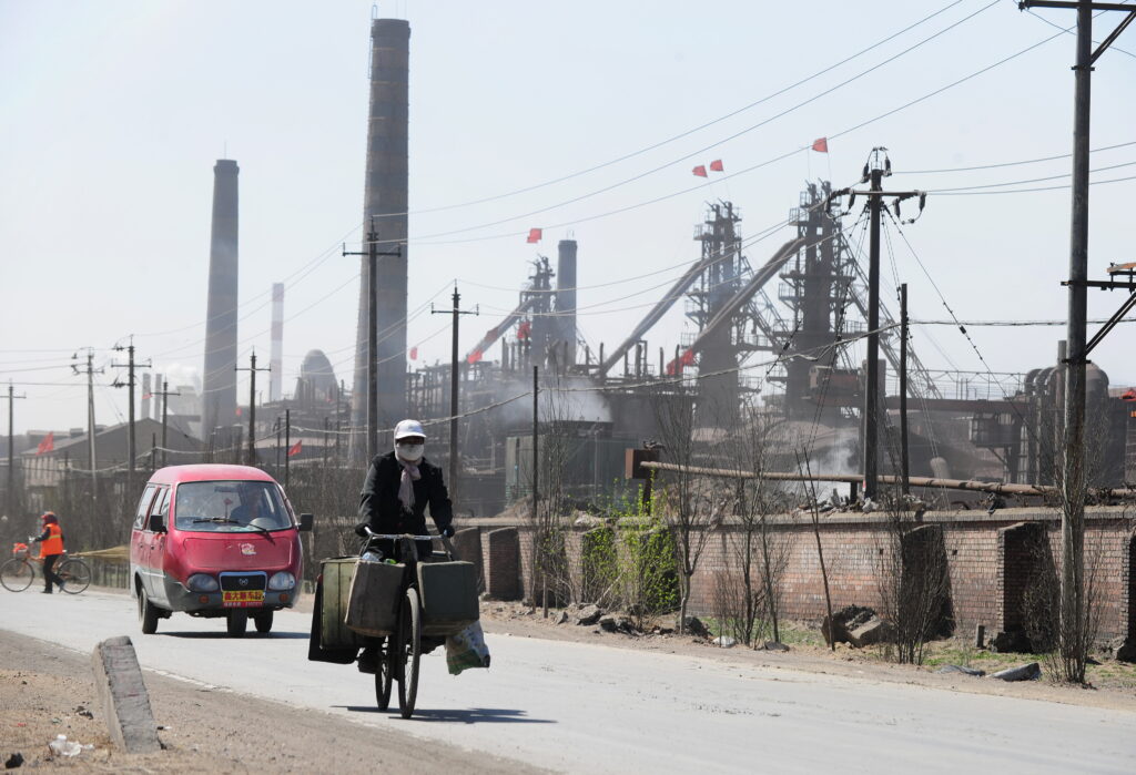 Masked cyclist riding past industrial zone