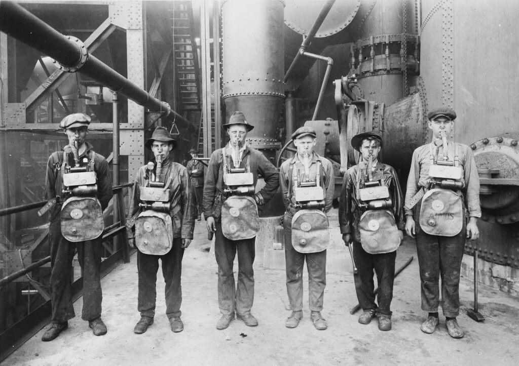 Old photo of a group of men wearing cumbersome gas masks