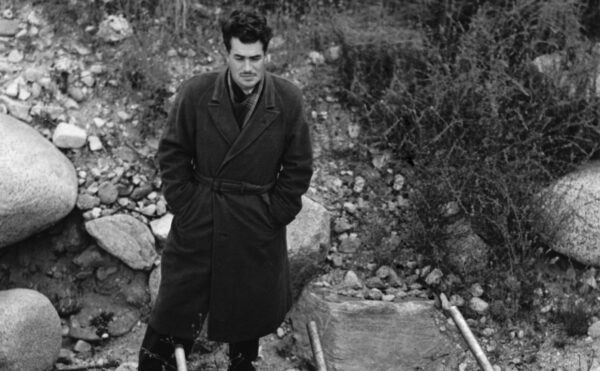 Photo of man standing near rocks and a canister