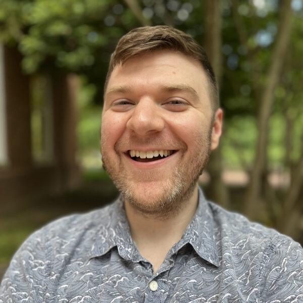 Jacob Myer outdoors in front of trees, smiling