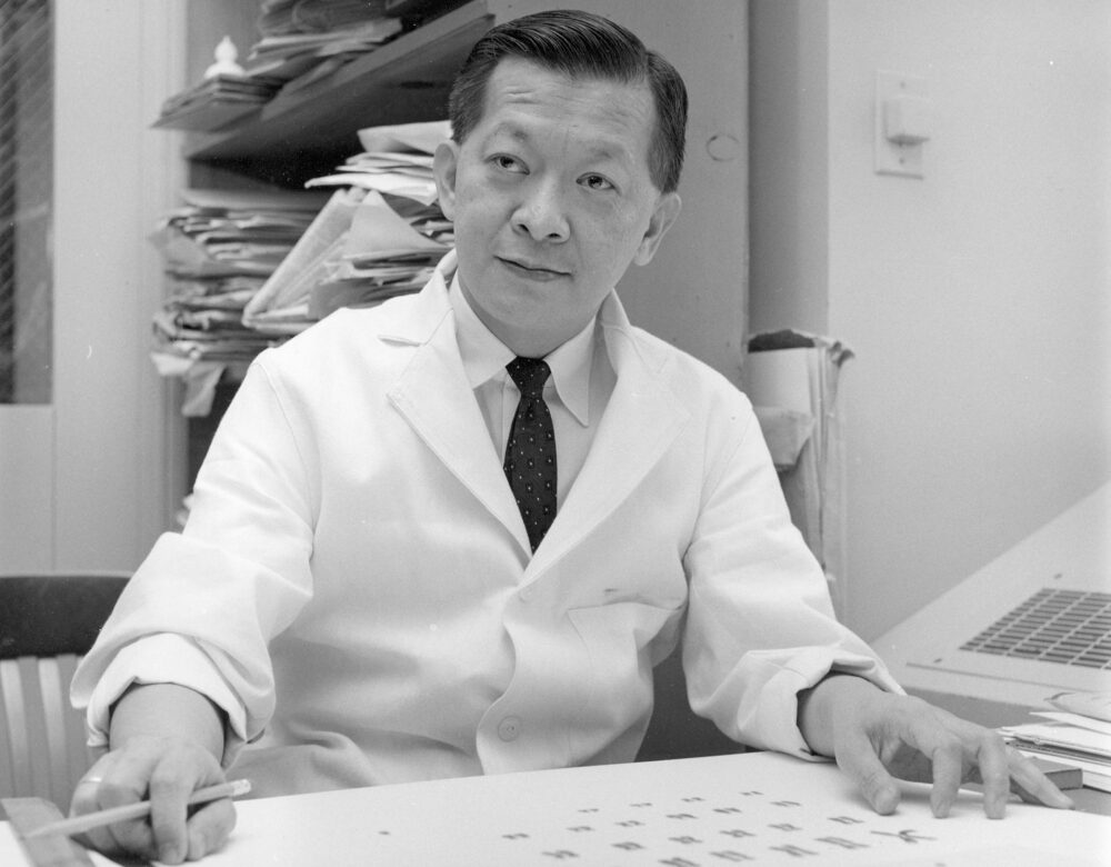 black and white photo of a seated man in a lab coat