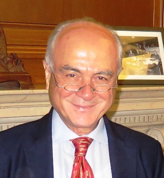 Kenan E. Sahin wearing glasses mid-nose, navy jacket, white shirt, red and gold tie