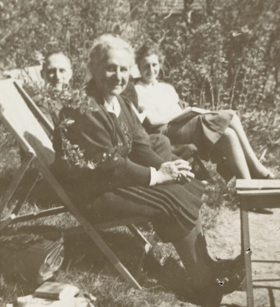 Old black and white photo of people lounging outside