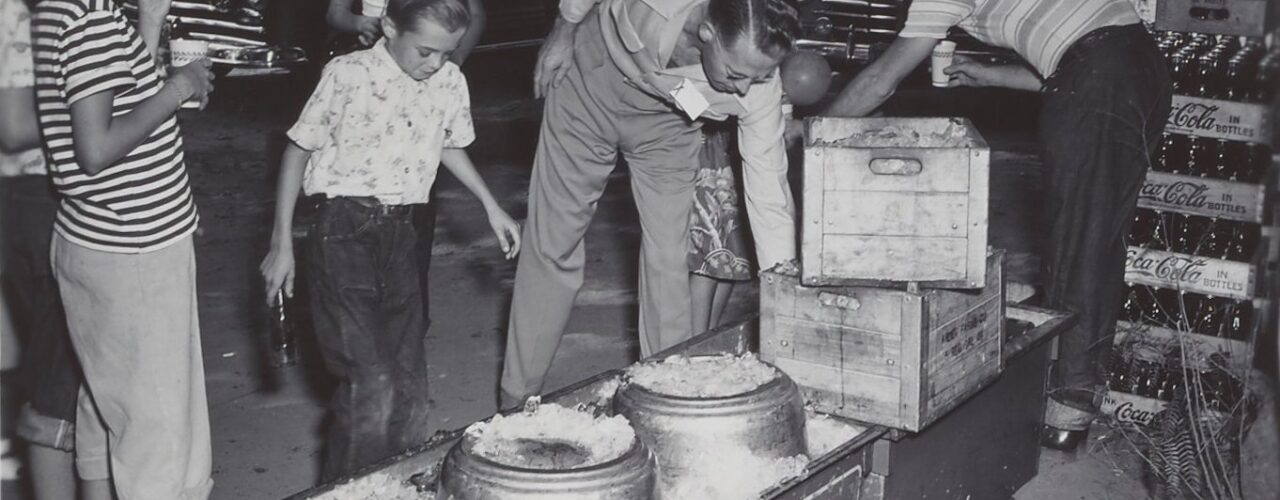 People at a picnic reaching into Coca-Cola coolers filled with ice