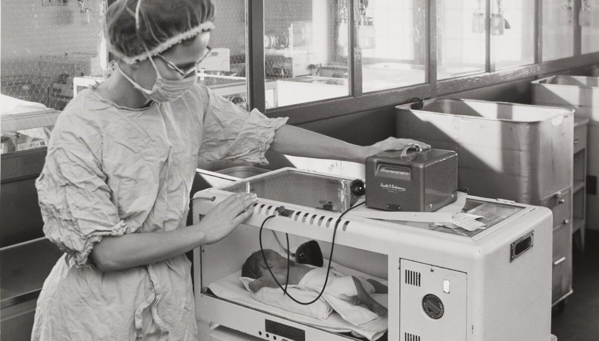 nurse monitoring an infant in a incubaor