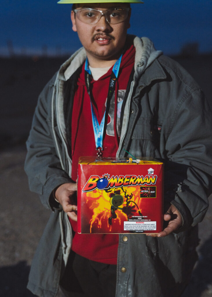 Man in dark in hardhat holding large, branded firework