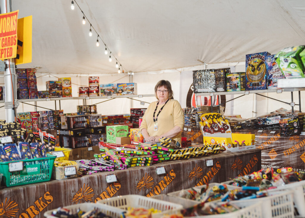 Woman standing in tent with large selection of fireworks