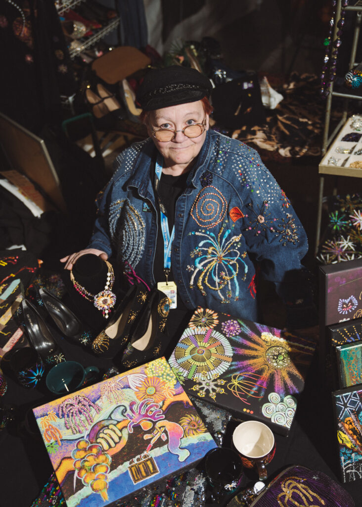 Woman in bedazzled clothes standing in booth with clothes and jewelry