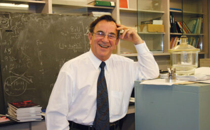 Man smiling in front of a chalk board