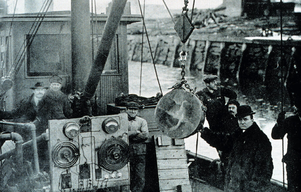 Black and white photo of men with equipment on ship