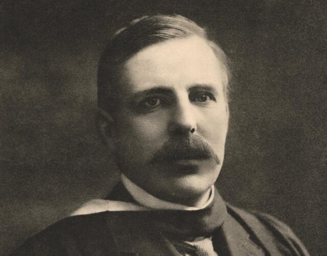 Rutherford with a thick mustache wearing a dark three-piece suit