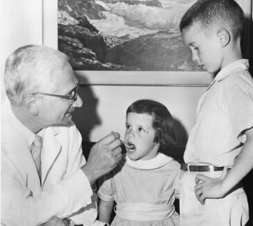 Albert Sabin demonstrates how the oral vaccine for polio is given to children.