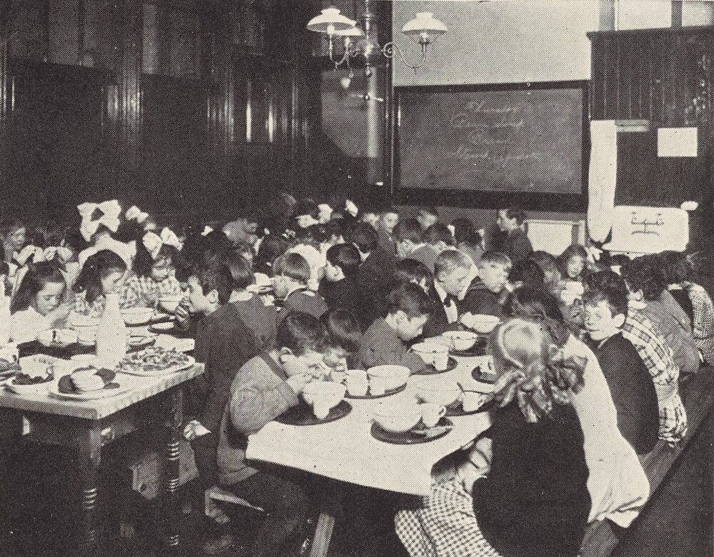 black and white photo of kids eating at tables