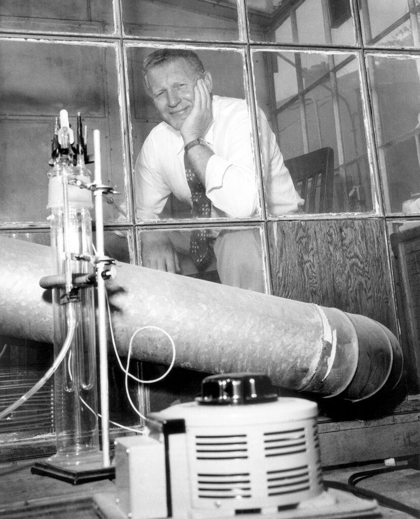 Man seated and smiling in a greenhouse-like shed